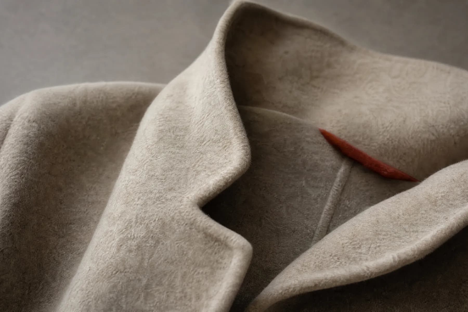 A wool jacket lapel curving in a soft roll rather than a pressed crease.